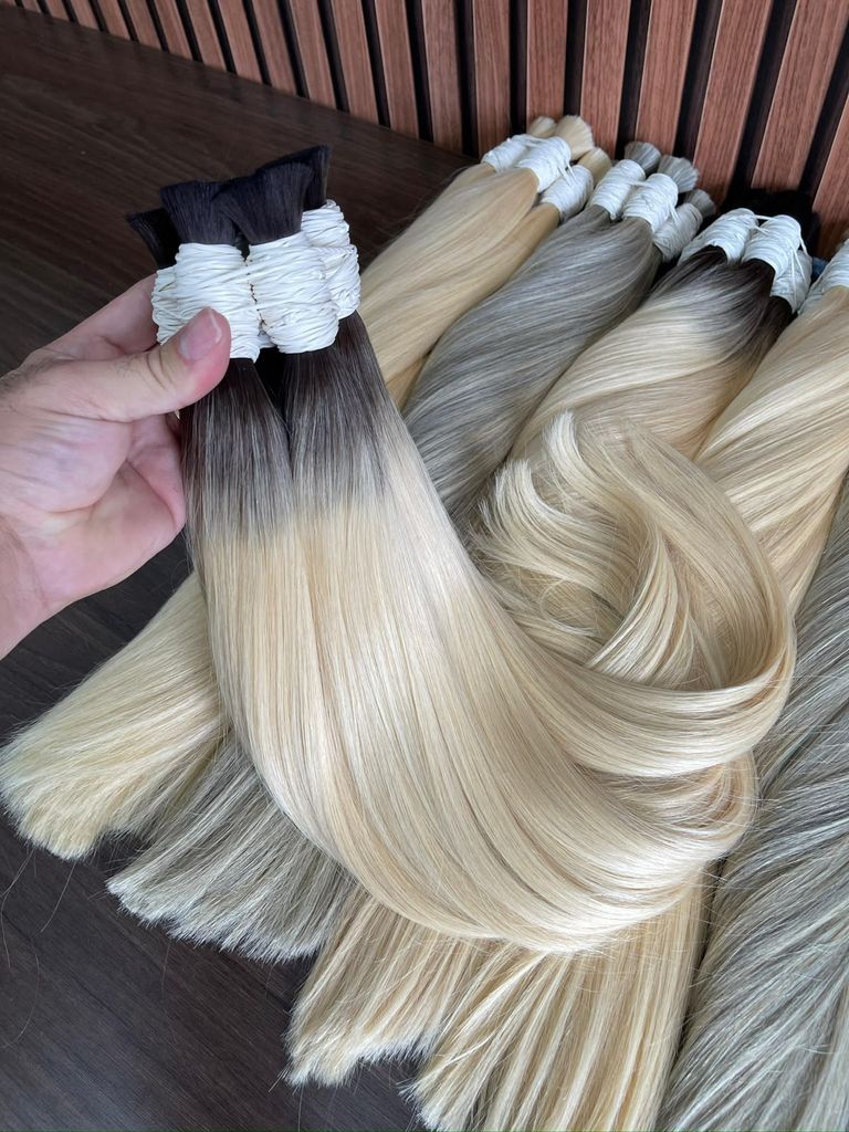 Mechas de mega hair loiro com raiz esfumada escura, lisas, sobre uma mesa de madeira
